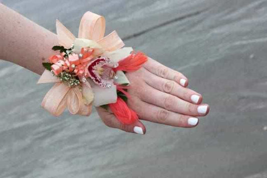 <p>A stunning White Cymbidium Orchid mounted on an orange background to create this striking corsage.</p><p>Providing glamour and drama the orchid is mounted on a beautiful pearl wristband.</p>