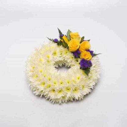 <p>A Classic meaningful arrangement. Created on a 25cm ring (10") and decorated using a mass of double headed chrysanthimums  and decorated with a touch of colour using roses.</p><p>In the examples shown yellow roses are used to decorate, simply contact us with your requirements if other colours are preferred.</p>